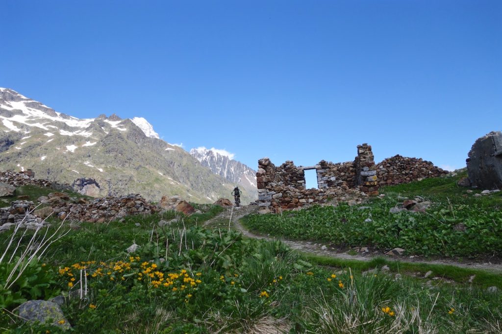 Mountain Biker riding past some old ruins Alps